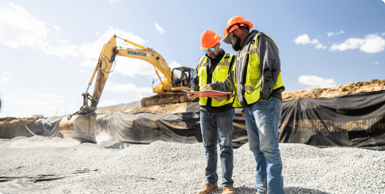 Site supervisors going over plans near an excavator